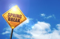 spring break text on yellow traffic sign with sky background